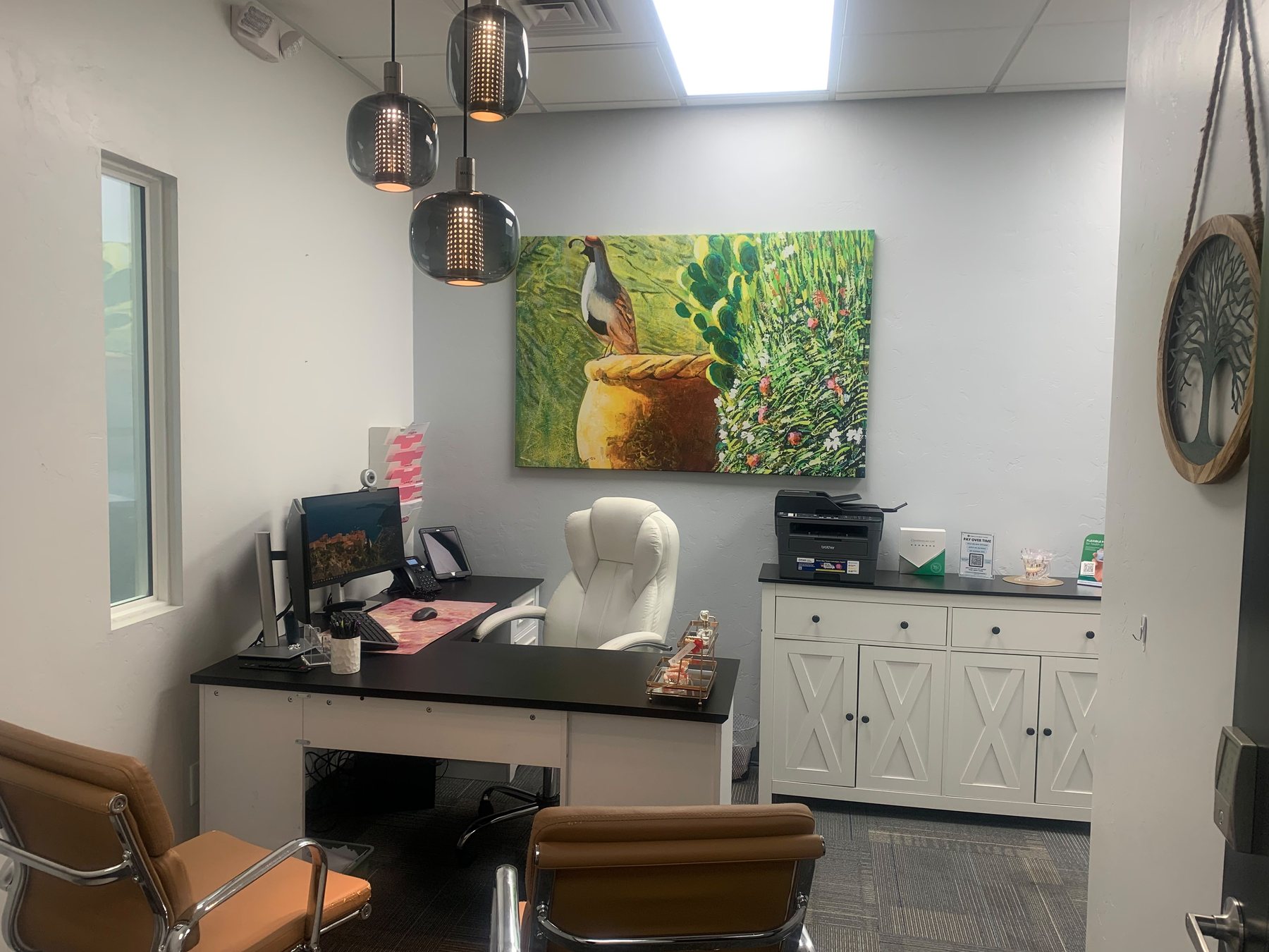 A consultation room with a desk and two chairs, set up for talking rather than treatment