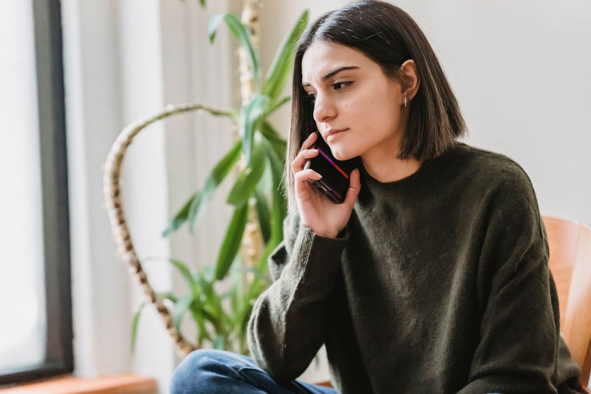 Woman making a phone call from home, concerned but composed