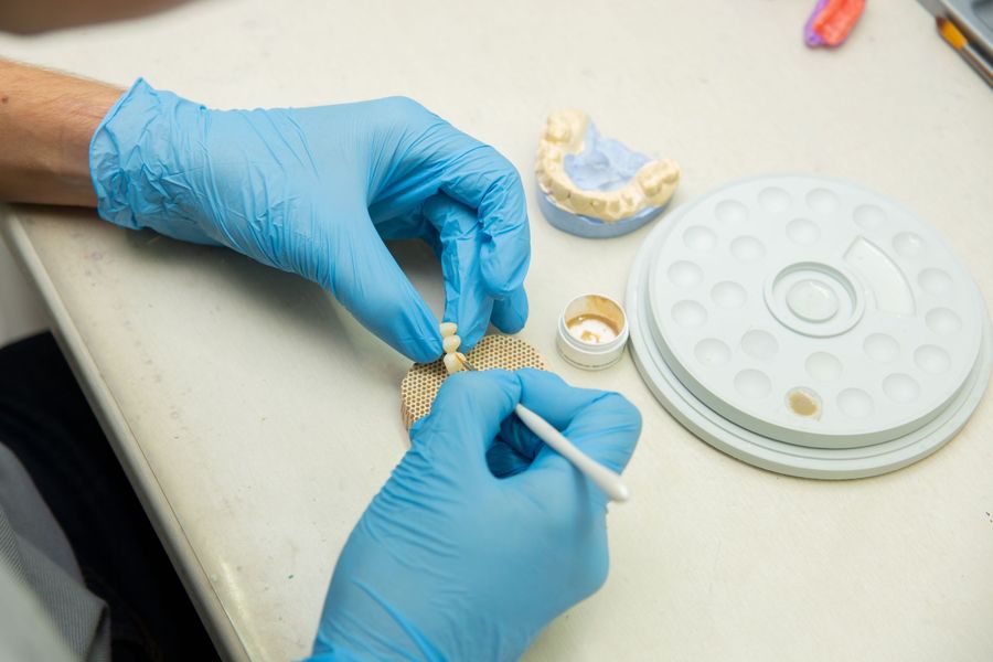 Dental technician shaping a multi-unit bridge on a firing tray